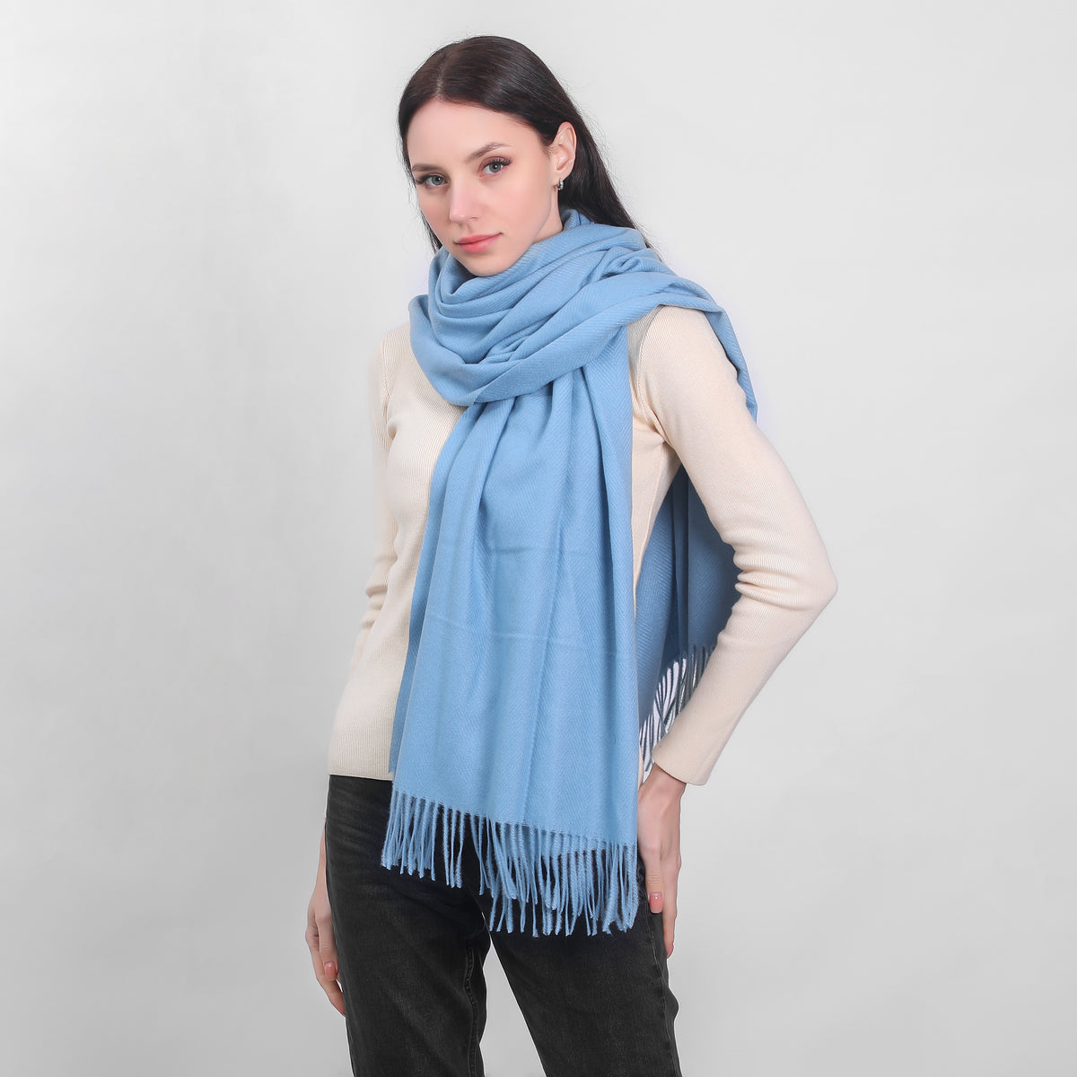 Woman wearing a large light blue scarf and beige sweater posing