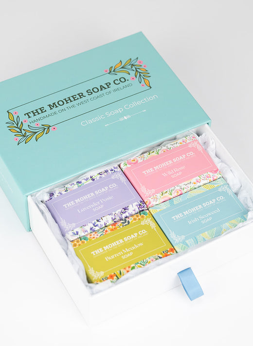 Open box with four colorful handmade soap bars arranged inside