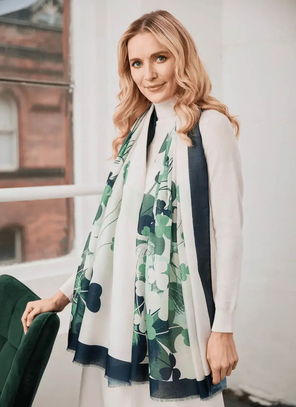 Blonde woman wearing white outfit and floral patterned scarf indoors