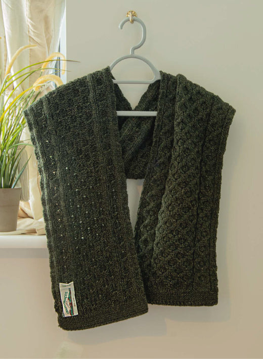 Dark green knitted scarf hanging on a gray hanger near a window
