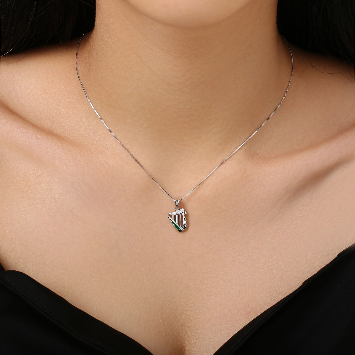 Silver harp-shaped pendant necklace worn on a woman's neck