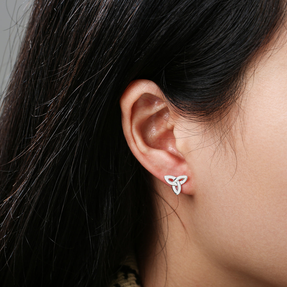 Close-up of ear wearing silver triquetra knot stud earring