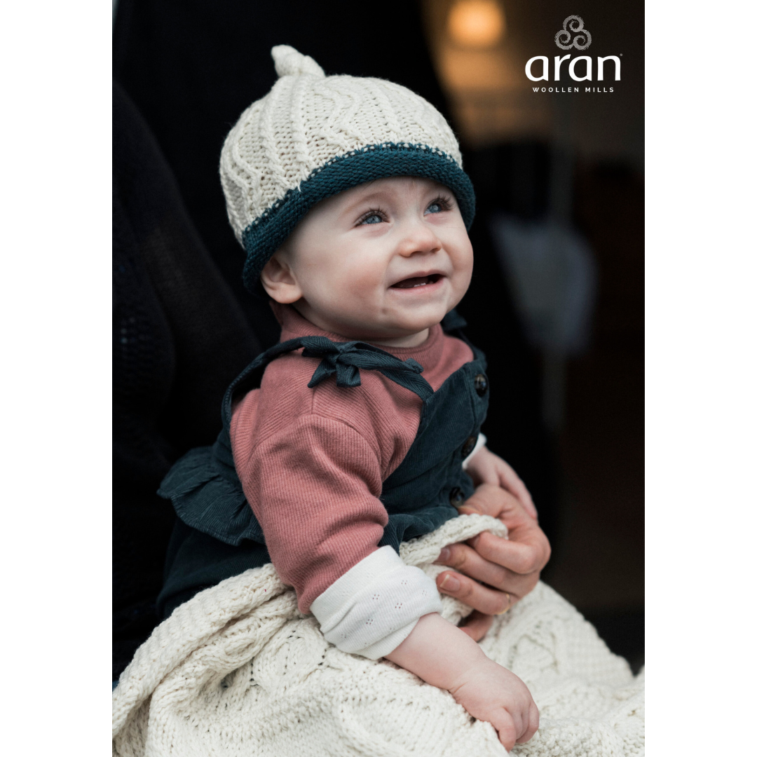 Smiling baby wearing knitted hat and warm clothes sitting on a blanket