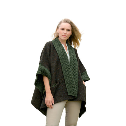 Woman wearing dark poncho with green knitted collar and beige pants