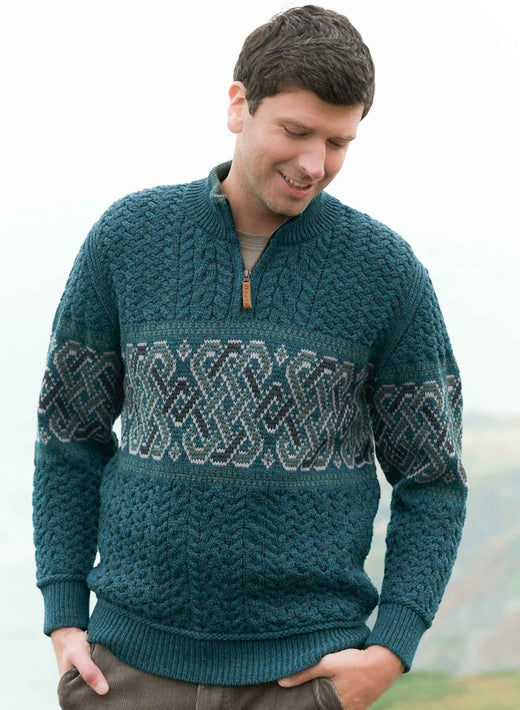 Man wearing teal cable knit sweater with patterned band across chest and sleeves