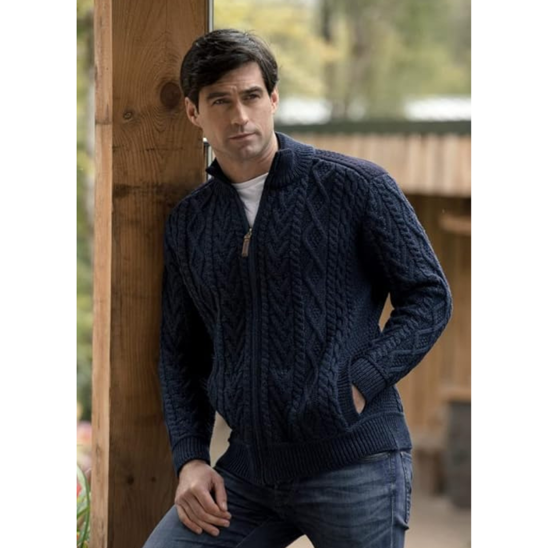 Man wearing navy blue cable knit zip-up sweater leaning on wooden post