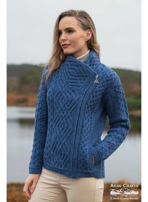 Woman wearing a blue cable knit sweater standing outdoors near water