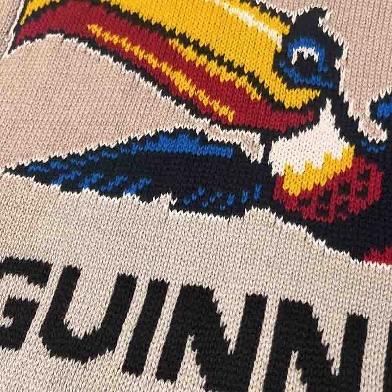 Close-up of beige Guinness Flying Toucan jumper with a colorful bird graphic