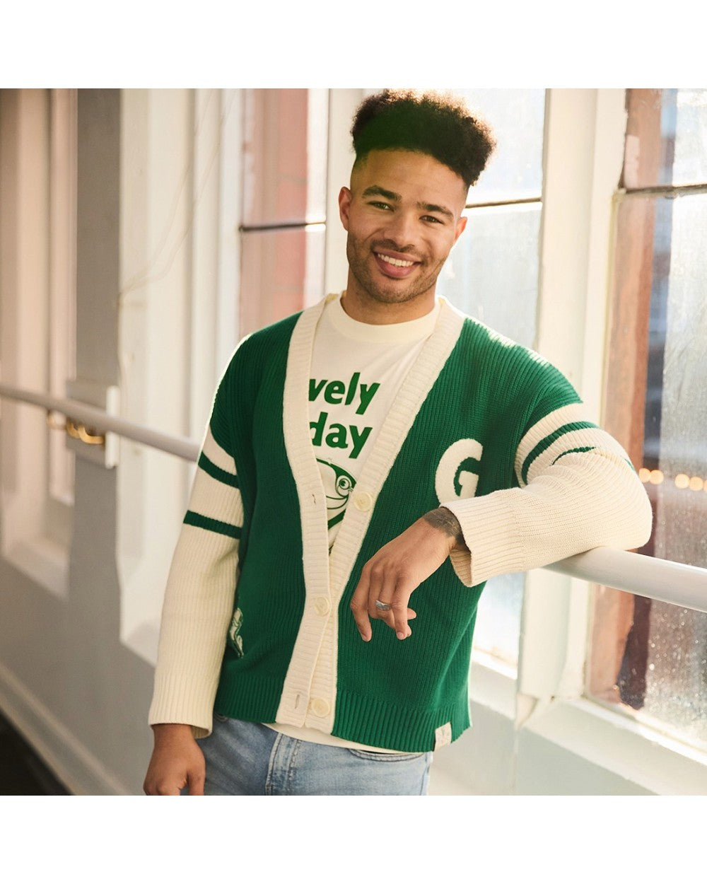 Male model wearing green and cream knitted cardigan with cream sleeves and white button placket.