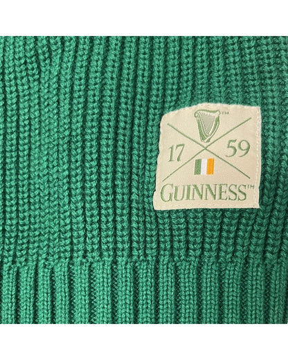 Close up of green knitted fabric with a beige Guinness patch featuring a harp and Irish flag.