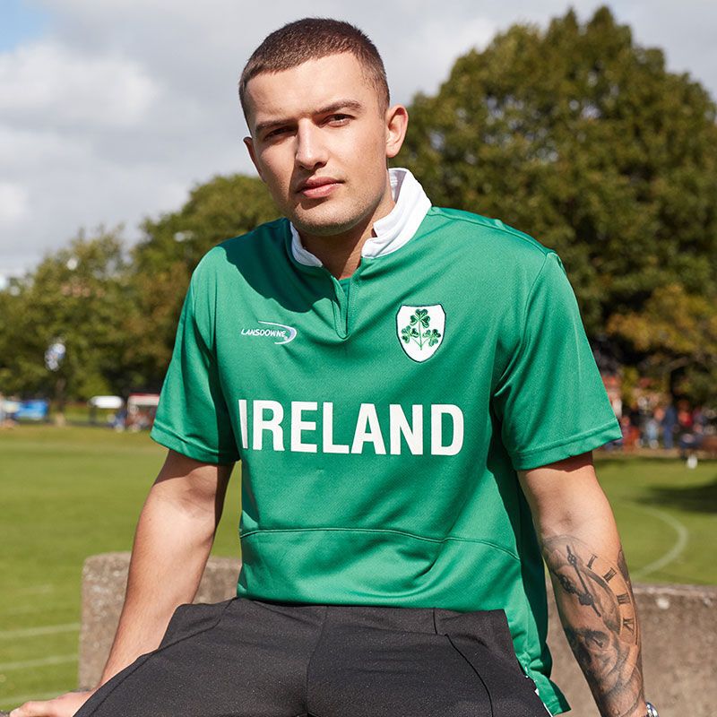 Young man wearing green Ireland sports jersey sitting outdoors