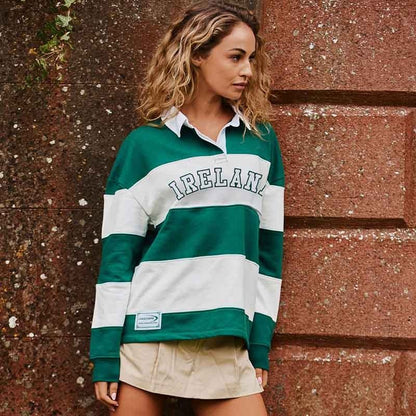 Model wearing a green and white striped Lansdowne Ireland rugby polo shirt.