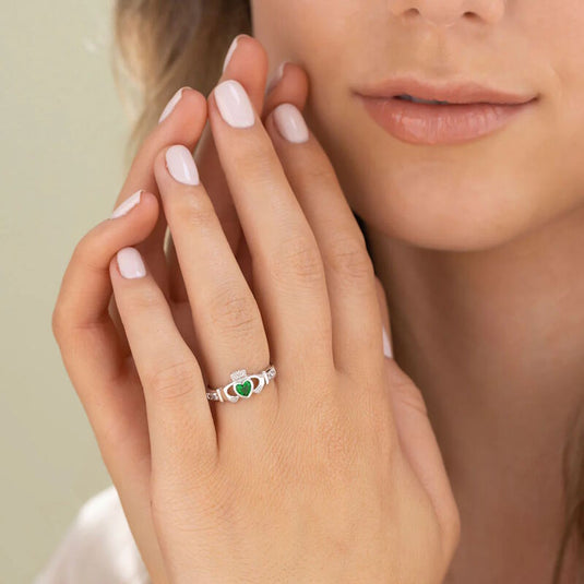 Close-up of hand with silver ring featuring a green heart-shaped stone