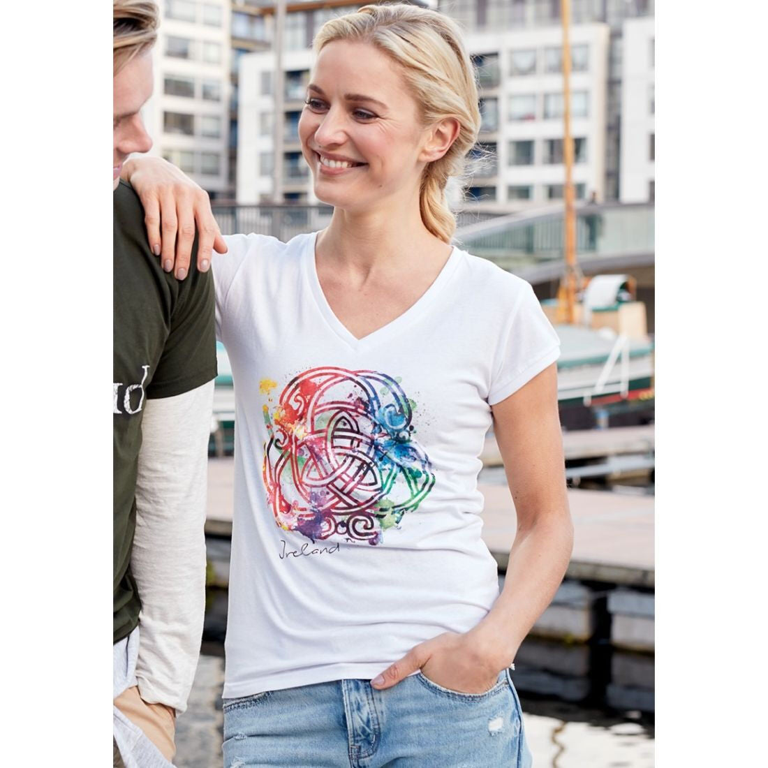 Smiling woman wearing a white V neck T shirt with a colorful Celtic knot design