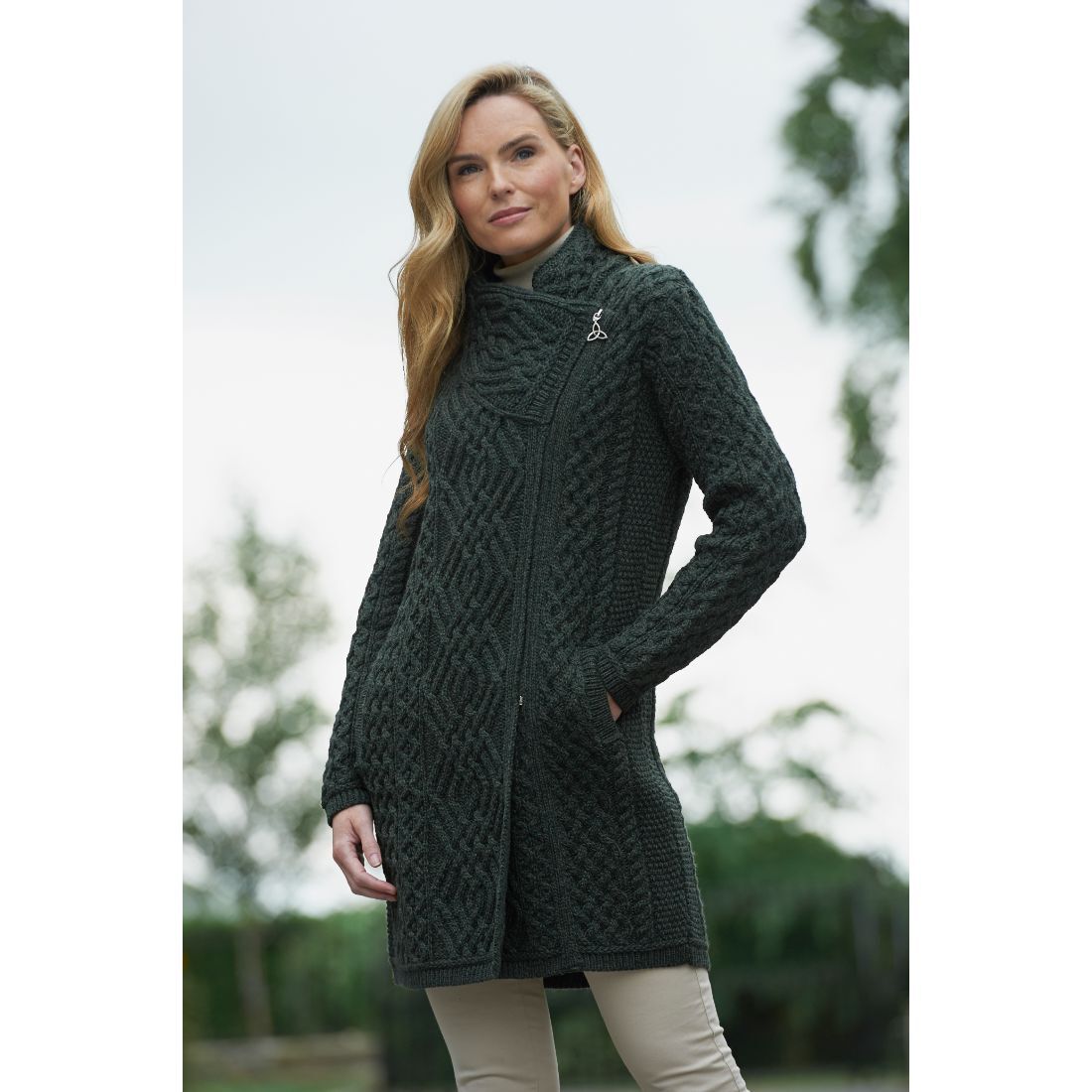 Woman wearing dark green cable knit long cardigan outdoors